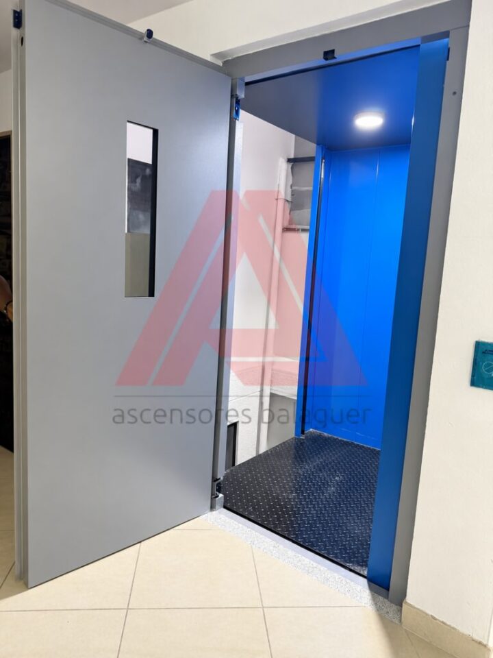 Cabina del montacargas hidráulico de 2 toneladas vista desde la puerta de piso abierta, en Medellín